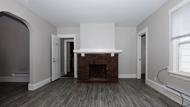 312 N Mclean St, Bloomington, IL 61701 - unfurnished living room with dark wood-type flooring, a brick fireplace, a baseboard radiator, and arched walkways