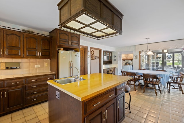 10 Shoreside Dr, South Barrington, IL 60010 - kitchen featuring freestanding refrigerator, a kitchen island with sink, decorative backsplash, pendant lighting, and tile counters