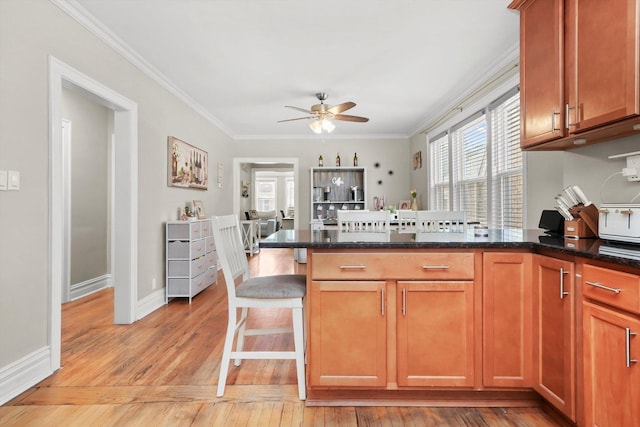3115 N Marmora Ave, Chicago, IL 60634 - kitchen with a peninsula, ceiling fan, a breakfast bar area, crown molding, and light wood-style flooring