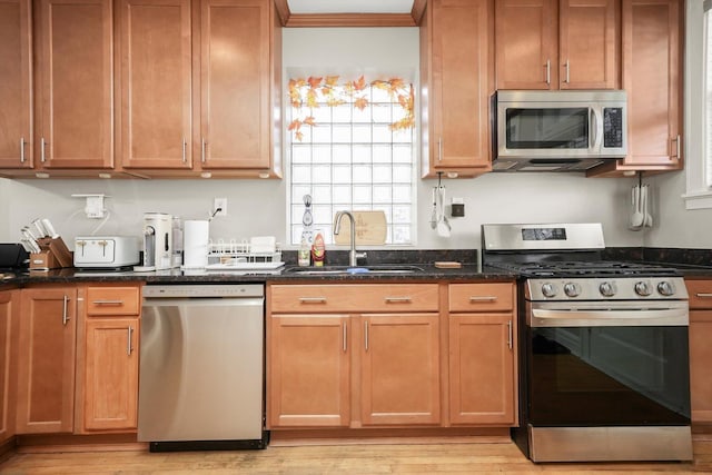 3115 N Marmora Ave, Chicago, IL 60634 - kitchen with appliances with stainless steel finishes, light wood-style flooring, dark stone countertops, ornamental molding, and brown cabinetry
