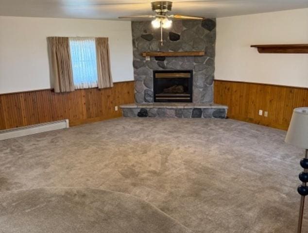 12238 Lisbon Rd, Newark, IL 60541 - unfurnished living room with a wainscoted wall, wooden walls, a ceiling fan, a fireplace, and a baseboard heating unit