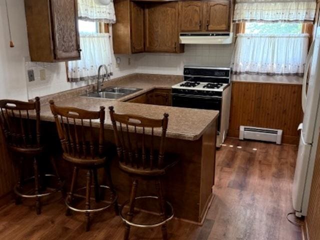 12238 Lisbon Rd, Newark, IL 60541 - kitchen featuring a baseboard heating unit, white appliances, under cabinet range hood, a peninsula, and dark wood finished floors