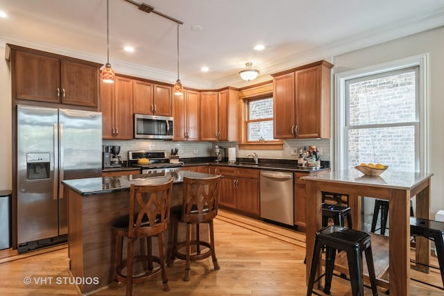 4933 N Winthrop Ave Unit 2S, Chicago, IL 60640 - kitchen featuring stainless steel appliances, a kitchen island, backsplash, light wood-style flooring, and ornamental molding