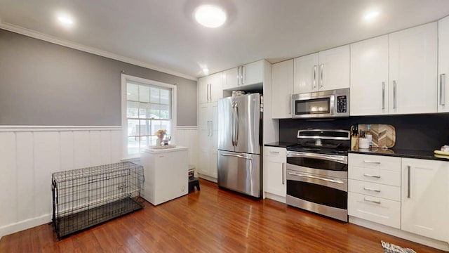 16 W George St, Sullivan, IL 61951 - kitchen with appliances with stainless steel finishes, dark countertops, white cabinets, ornamental molding, and wainscoting