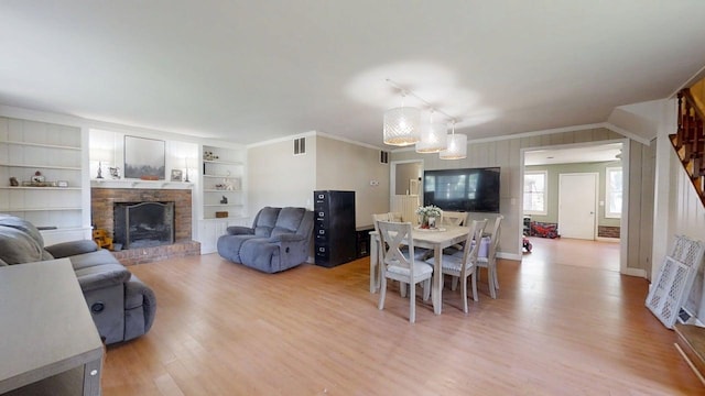 16 W George St, Sullivan, IL 61951 - living area featuring light wood-style flooring, a fireplace with raised hearth, ornamental molding, and built in features