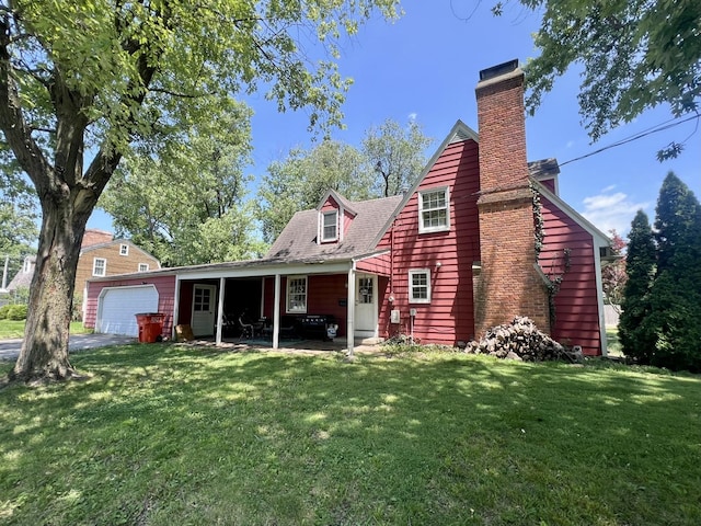 16 W George St, Sullivan, IL 61951 - rear view of property with a lawn, a chimney, an attached garage, and driveway