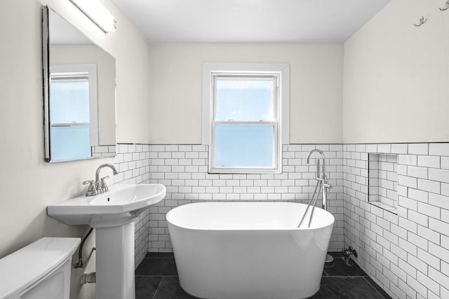 1212 Wesley Ave, Berwyn, IL 60402 - bathroom featuring tile walls, tile patterned flooring, a freestanding bath, and a wainscoted wall