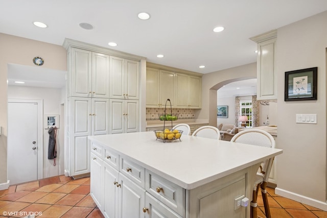 1415 Keystone Ave, River Forest, IL 60305 - kitchen featuring arched walkways, a breakfast bar area, backsplash, light tile patterned flooring, and a center island