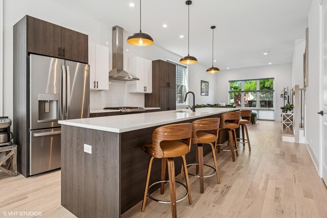 4535 S Evans Ave, Chicago, IL 60653 - kitchen with wall chimney range hood, stainless steel refrigerator with ice dispenser, a large island with sink, modern cabinets, and light countertops