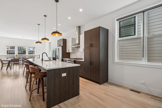 4535 S Evans Ave, Chicago, IL 60653 - kitchen with wall chimney exhaust hood, a breakfast bar, an island with sink, light wood-style floors, and range
