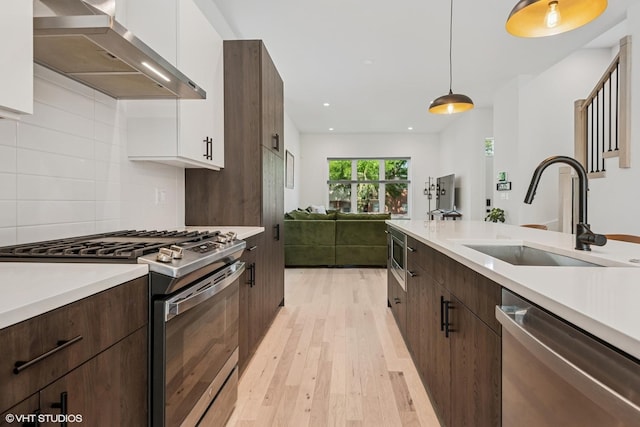 4535 S Evans Ave, Chicago, IL 60653 - kitchen with stainless steel appliances, wall chimney range hood, light wood-type flooring, white cabinets, and light countertops
