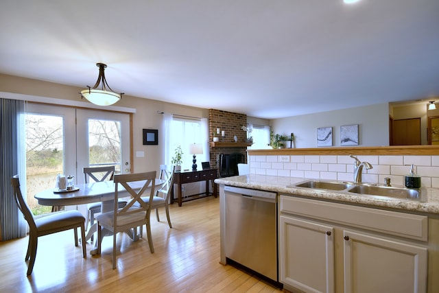2146 Prairie Trl, Round Lake Heights, IL 60073 - kitchen featuring stainless steel dishwasher, tasteful backsplash, a brick fireplace, light wood-type flooring, and hanging light fixtures