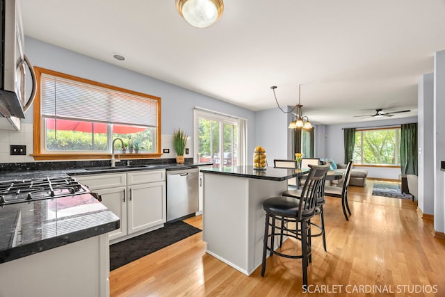 908 Pimpernel Ct, Naperville, IL 60540 - kitchen featuring appliances with stainless steel finishes, light wood finished floors, a kitchen bar, white cabinets, and hanging light fixtures