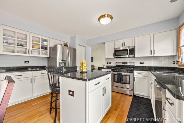 908 Pimpernel Ct, Naperville, IL 60540 - kitchen with stainless steel appliances, light wood-type flooring, white cabinets, a kitchen island, and glass insert cabinets