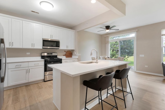 13315 Red Alder Ave, Huntley, IL 60142 - kitchen featuring stainless steel appliances, light wood-type flooring, a center island with sink, white cabinetry, and ceiling fan
