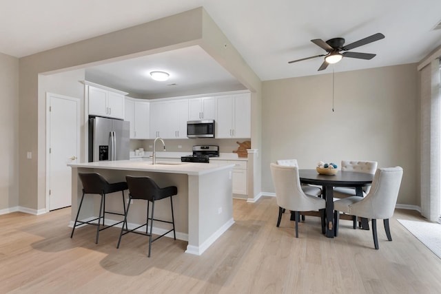 13315 Red Alder Ave, Huntley, IL 60142 - kitchen featuring appliances with stainless steel finishes, light wood-style floors, light countertops, a ceiling fan, and a breakfast bar area