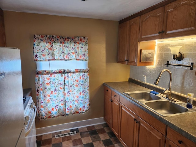 711 Avenue E Ave E, Sterling, IL 61081 - kitchen with freestanding refrigerator, white gas range, brown cabinetry, decorative backsplash, and crown molding