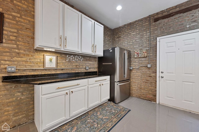 2627 N Kimball Ave Unit 2A, Chicago, IL 60647 - kitchen featuring freestanding refrigerator, light tile patterned flooring, white cabinets, and brick wall
