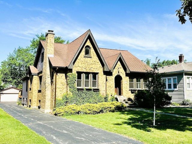 314 N Maple St, Itasca, IL 60143 - tudor-style house with brick siding, an outdoor structure, a front lawn, a chimney, and a detached garage