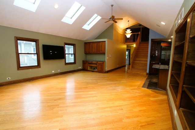 314 N Maple St, Itasca, IL 60143 - unfurnished living room with a skylight, light wood-type flooring, a ceiling fan, stairway, and high vaulted ceiling