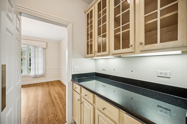 775 S Camelot Ct, Lake Forest, IL 60045 - kitchen featuring light wood finished floors, glass insert cabinets, dark countertops, cream cabinets, and ornamental molding