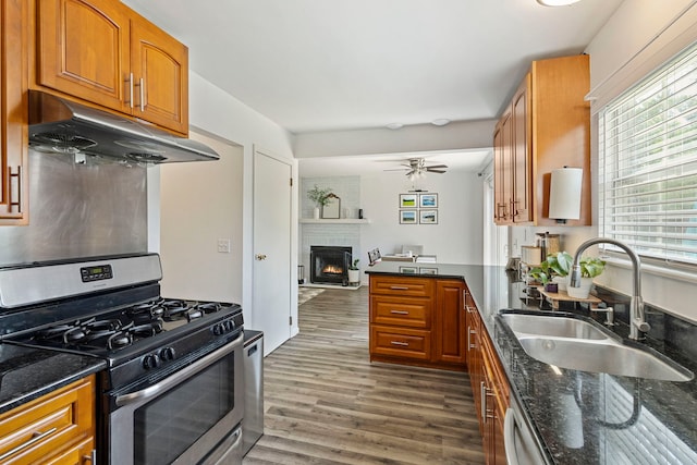 2011 University Dr, Naperville, IL 60565 - kitchen featuring stainless steel gas range, under cabinet range hood, brown cabinets, dark stone counters, and a fireplace