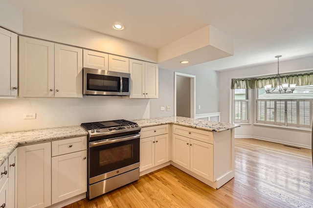 201 S Wulff St, Cary, IL 60013 - kitchen with stainless steel appliances, a peninsula, light wood finished floors, a chandelier, and recessed lighting