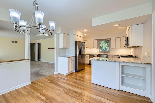 201 S Wulff St, Cary, IL 60013 - kitchen featuring appliances with stainless steel finishes, a chandelier, light stone counters, white cabinetry, and light wood-style floors