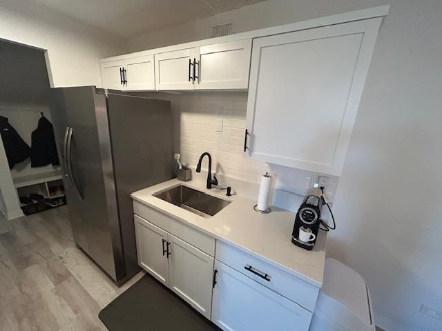 9098 Terrace Dr Unit 3E, Niles, IL 60714 - kitchen featuring stainless steel refrigerator with ice dispenser, light wood-type flooring, light countertops, decorative backsplash, and white cabinets
