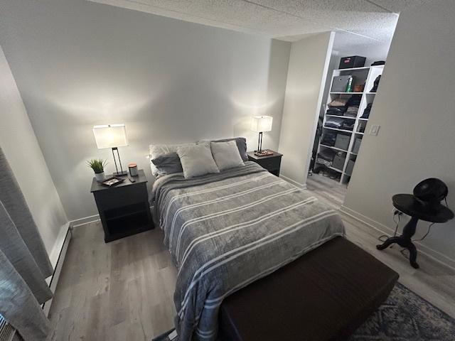 9098 Terrace Dr Unit 3E, Niles, IL 60714 - bedroom with wood finished floors, baseboard heating, a walk in closet, and a textured ceiling