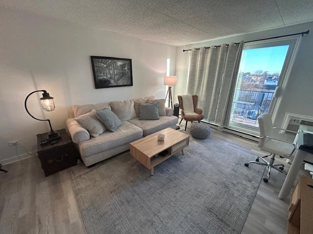 9098 Terrace Dr Unit 3E, Niles, IL 60714 - living room with wood finished floors, baseboard heating, and a textured ceiling