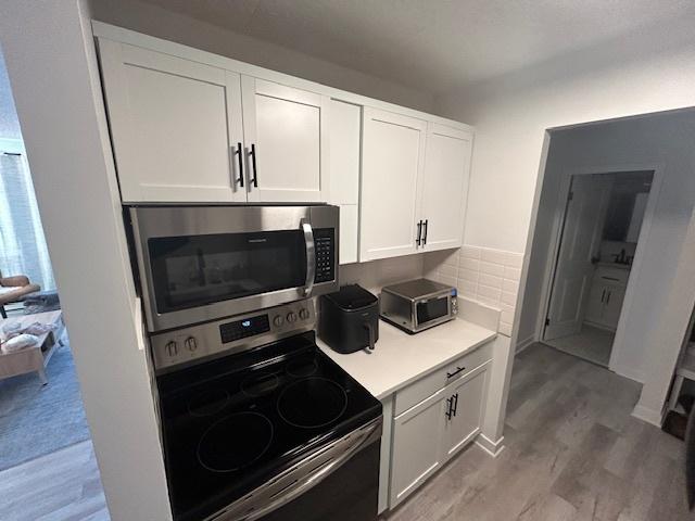 9098 Terrace Dr Unit 3E, Niles, IL 60714 - kitchen with stainless steel appliances, light wood-type flooring, light countertops, and white cabinets