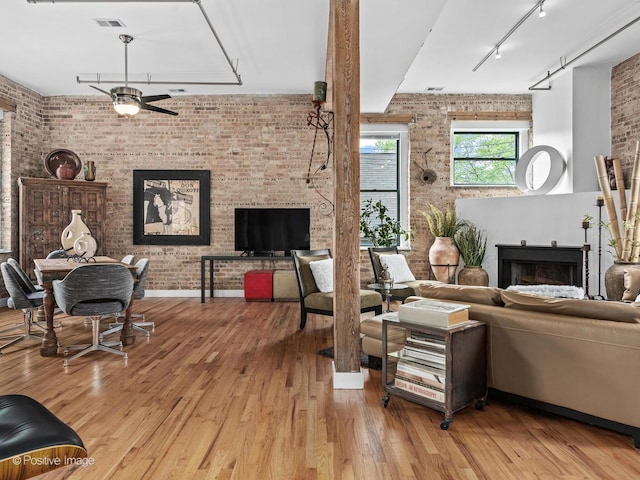 2035 W Charleston St Unit 205, Chicago, IL 60647 - living room with brick wall, track lighting, ceiling fan, a fireplace, and wood finished floors