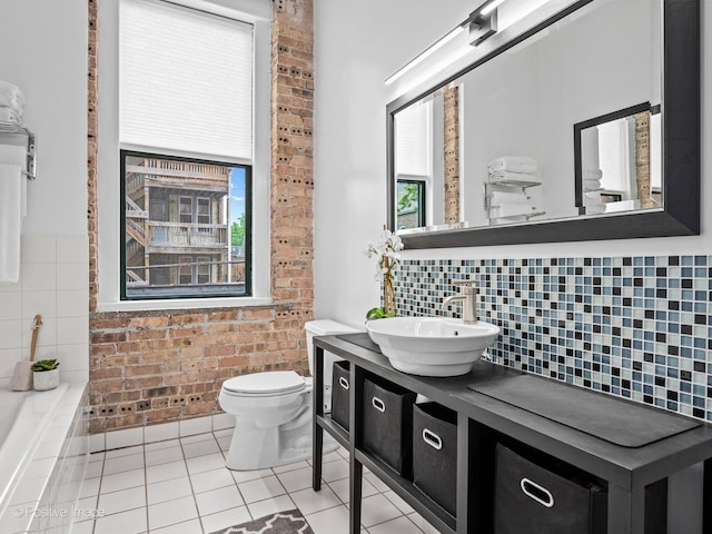 2035 W Charleston St Unit 205, Chicago, IL 60647 - full bathroom featuring vanity, tile patterned flooring, brick wall, tasteful backsplash, and a relaxing tiled tub