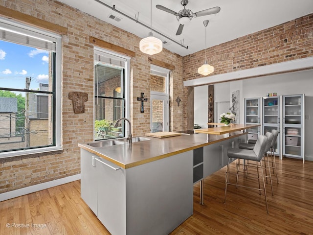 2035 W Charleston St Unit 205, Chicago, IL 60647 - kitchen with stainless steel countertops, brick wall, ceiling fan, wood finished floors, and pendant lighting