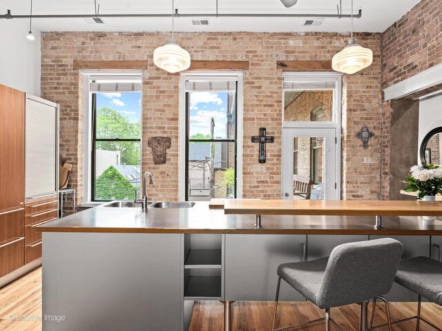 2035 W Charleston St Unit 205, Chicago, IL 60647 - kitchen featuring brick wall, a kitchen breakfast bar, and pendant lighting