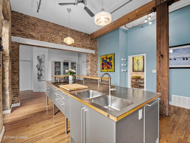 2035 W Charleston St Unit 205, Chicago, IL 60647 - kitchen featuring brick wall, stainless steel countertops, light wood-style flooring, dishwasher, and pendant lighting