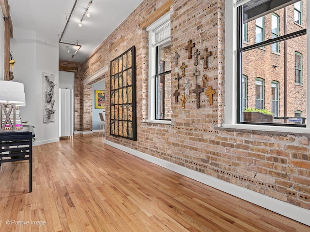 2035 W Charleston St Unit 205, Chicago, IL 60647 - hall featuring brick wall, rail lighting, healthy amount of natural light, wood finished floors, and a towering ceiling