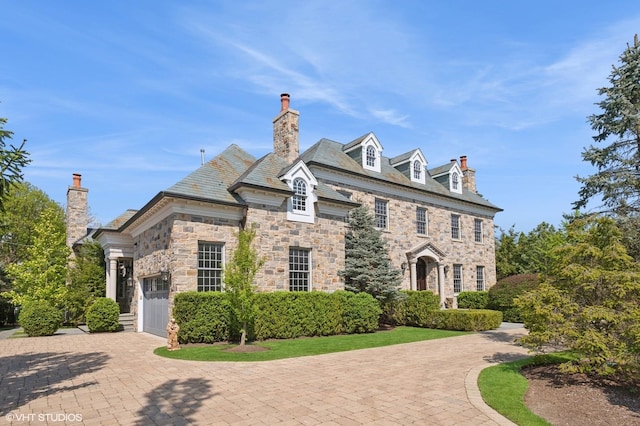 78 Wagner Rd, Northfield, IL 60093 - view of front of house featuring a high end roof, an attached garage, a chimney, and stone siding