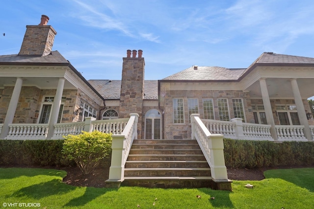 78 Wagner Rd, Northfield, IL 60093 - rear view of property with stone siding, a high end roof, a chimney, and a yard