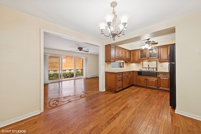 935 8th Ave Unit 1, La Grange, IL 60525 - kitchen featuring a chandelier, brown cabinets, baseboard heating, freestanding refrigerator, and tasteful backsplash