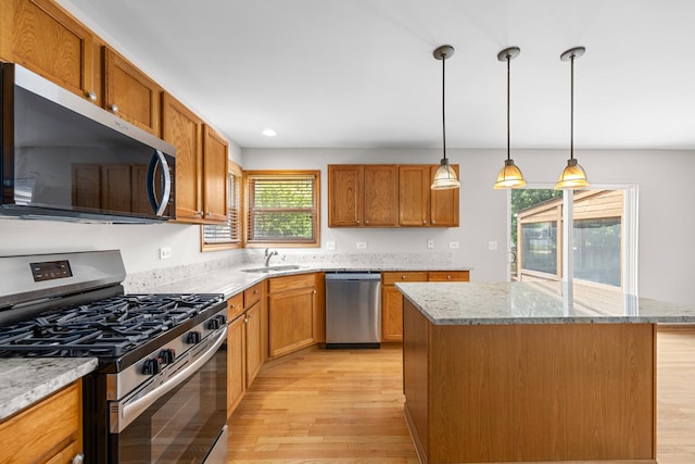 1301 Bridgehampton Dr, Plainfield, IL 60586 - kitchen with stainless steel appliances, light wood-type flooring, a kitchen island, brown cabinets, and pendant lighting