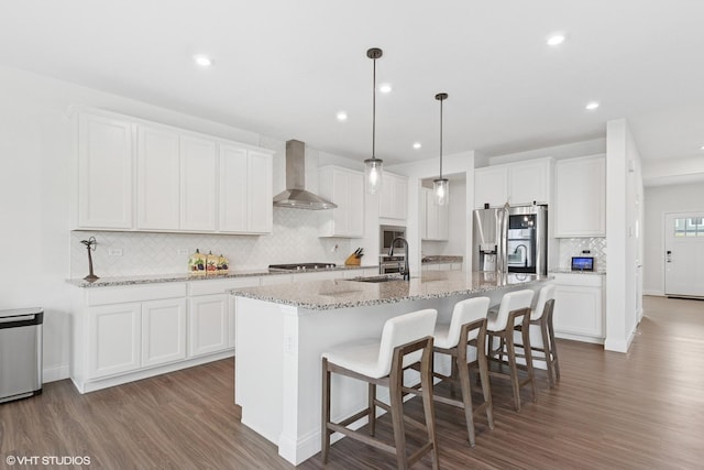12906 S Sydney Cir, Plainfield, IL 60585 - kitchen featuring appliances with stainless steel finishes, wall chimney exhaust hood, decorative backsplash, wood finished floors, and a center island with sink