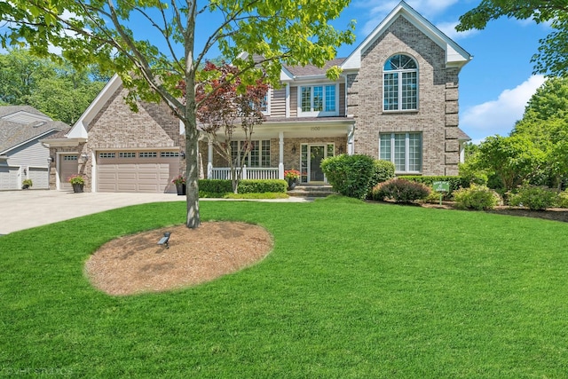 traditional home featuring brick siding, a front yard, a garage, and covered porch