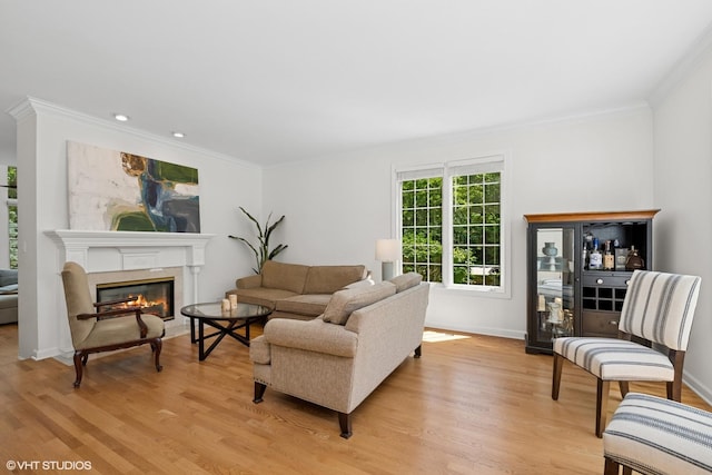 living room with ornamental molding, light wood-style flooring, a fireplace, and recessed lighting