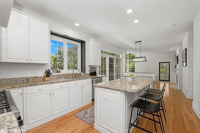 kitchen with dishwasher, a center island, recessed lighting, white cabinets, and light wood-style floors