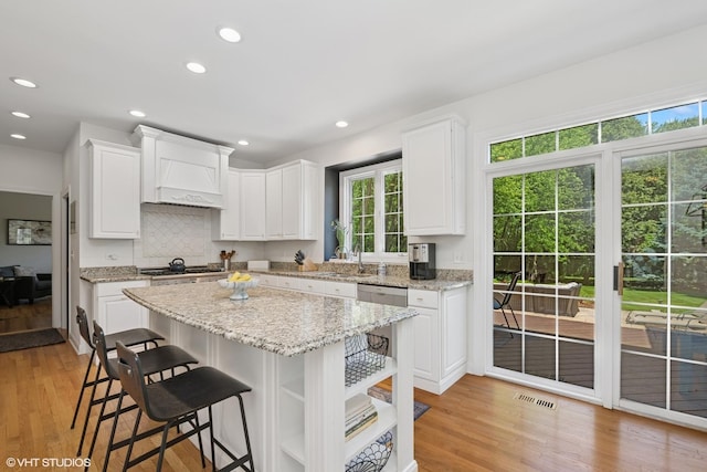 kitchen with healthy amount of natural light, white cabinets, custom exhaust hood, and recessed lighting