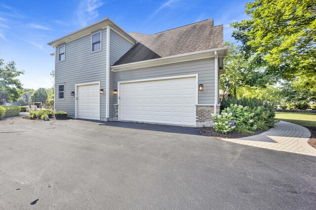 7270 Bannockburn Cir, Lakewood, IL 60014 - view of side of home featuring a shingled roof, asphalt driveway, and brick siding