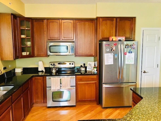 77 N Quentin Rd Unit 202, Palatine, IL 60067 - kitchen with stainless steel appliances, light wood-style flooring, glass insert cabinets, dark stone countertops, and brown cabinets