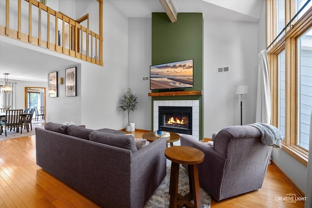 1809 Winmont Ct, Montgomery, IL 60538 - living room featuring a towering ceiling, a tile fireplace, wood finished floors, beam ceiling, and a chandelier